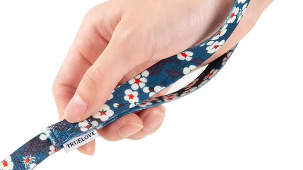 Mão segurando guia azul-marinho com estampa floral