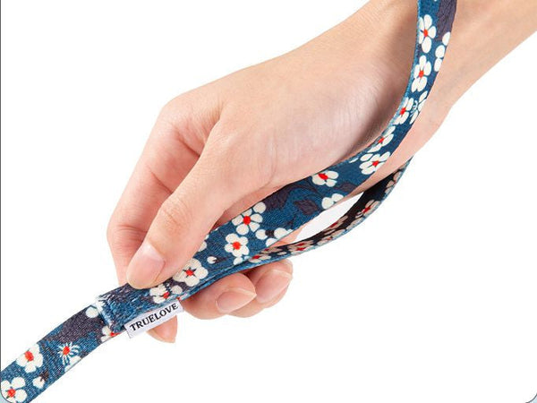 Mão segurando guia azul-marinho com estampa floral